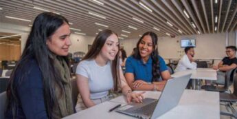 Three female students are sitting together and studying at a laptop.