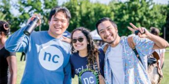 Three students are posing for the camera outdoors on a sunny day