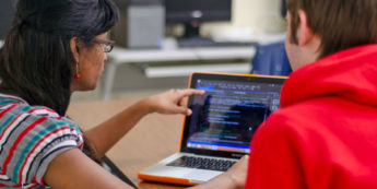 Student points at computer code on a laptop screen