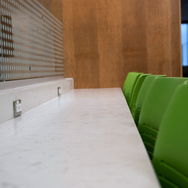 Row of green chairs with bar and plugs