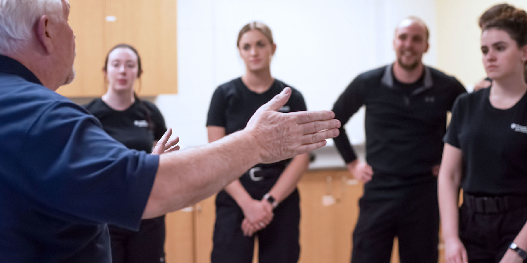 Standing instructor lecturing group of students wearing uniforms