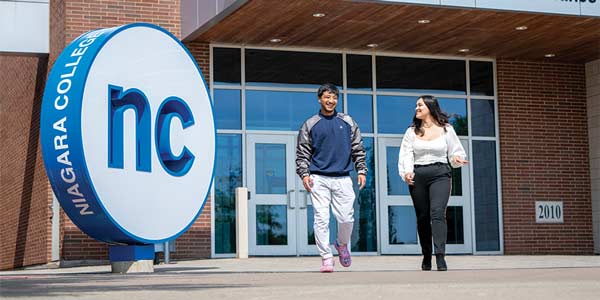 Two students walking in front of Niagara College Welland campus.