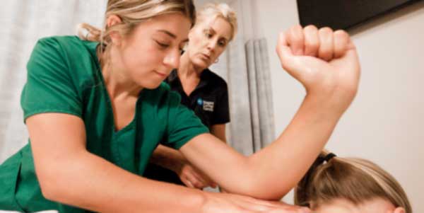Massage therapist student massaging client's back