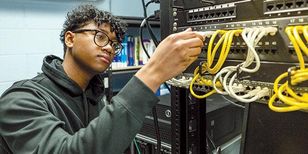 Male student working on network wiring for a server.