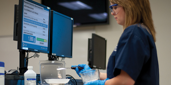 student working in classroom measuring out pharmacy ingredient
