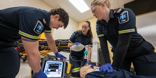 paramedic students using medical equipment on a practice dummy