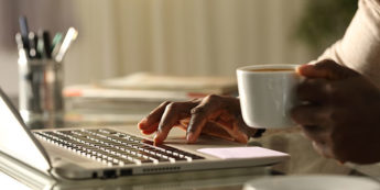 Person drinking coffee and working on laptop