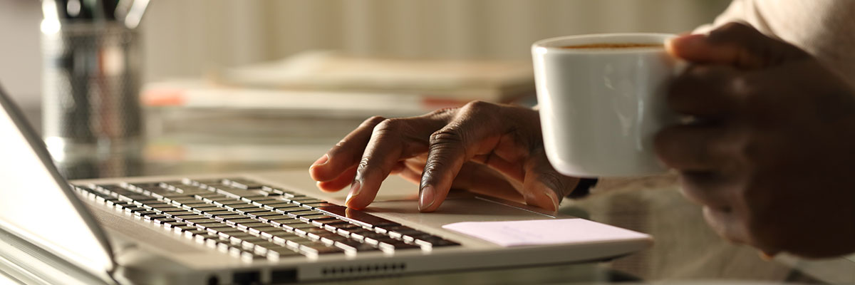 Person working on laptop holding coffee