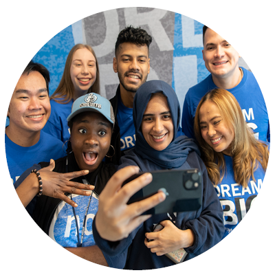 Group of diverse students posing and smiling for a selfie together.