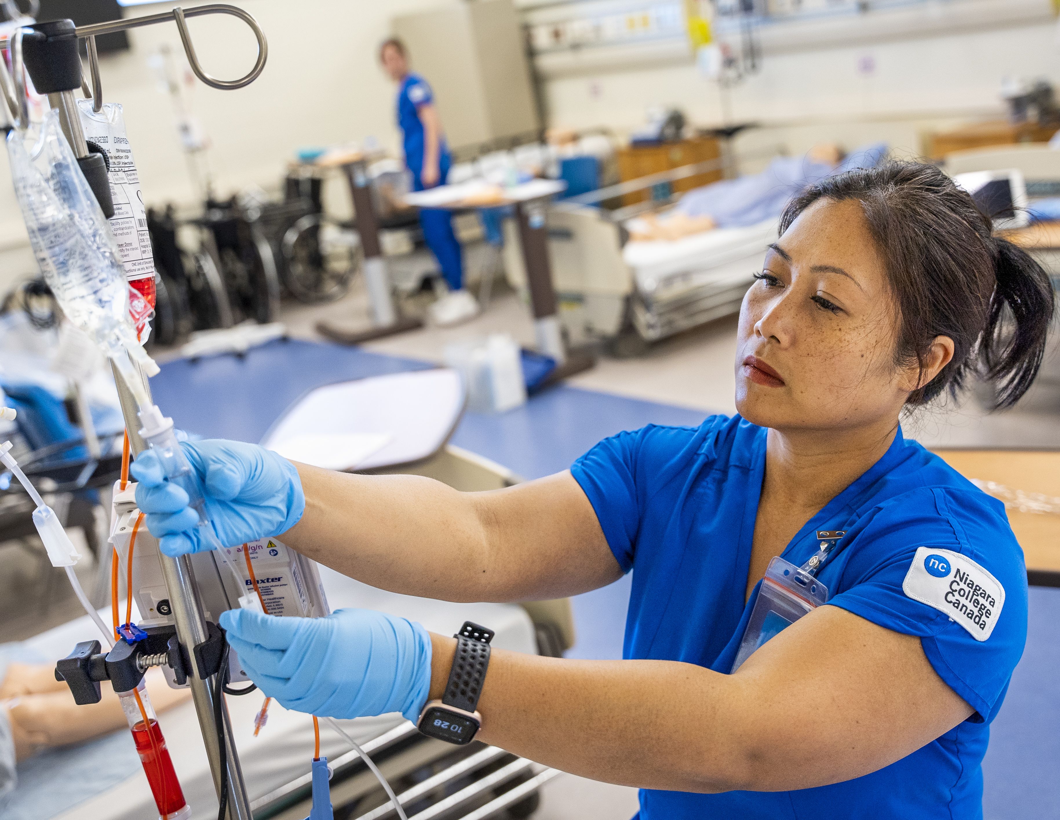 Nursing student inspects an IV line.