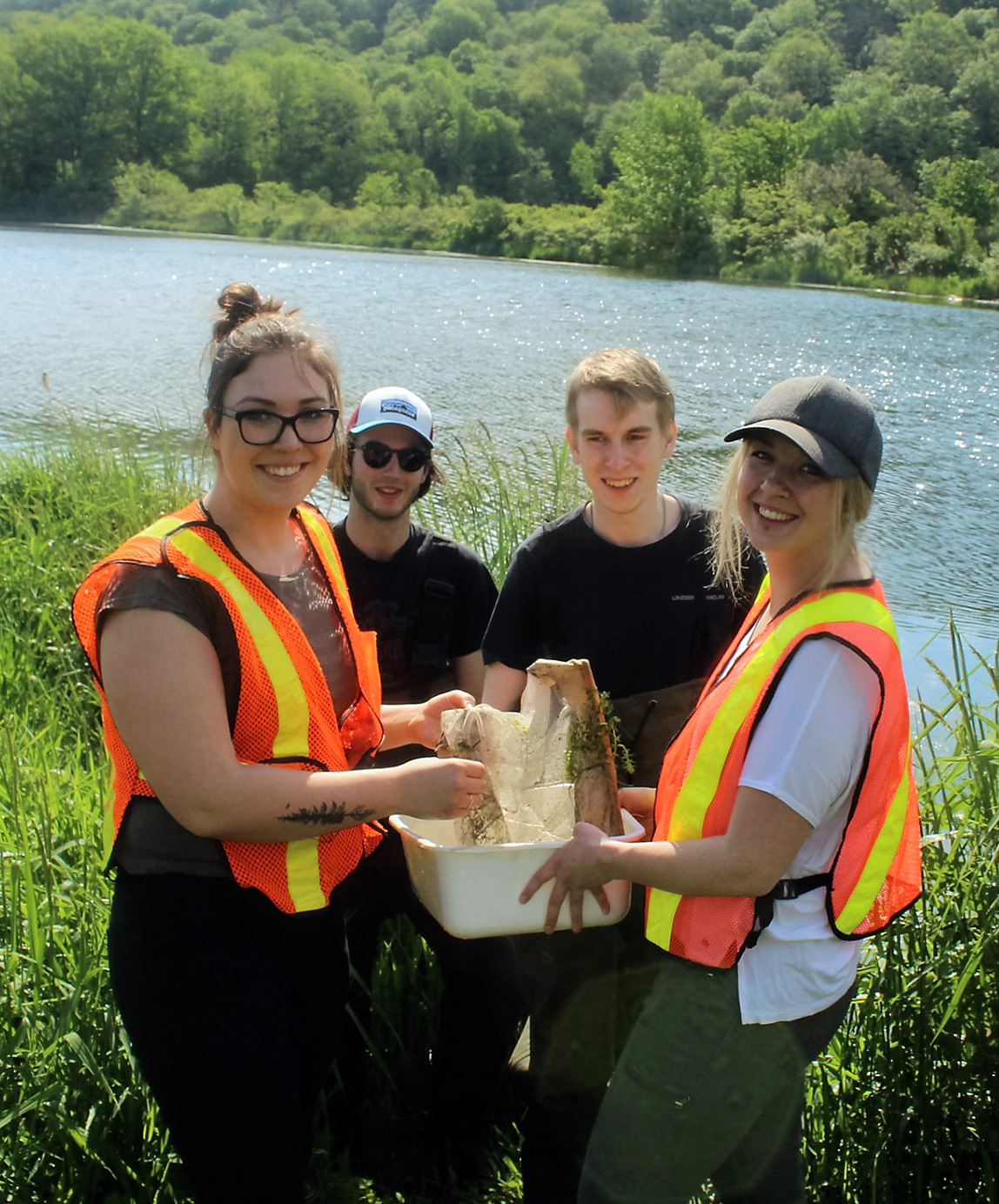 Students standing in front of lagoons holding a net