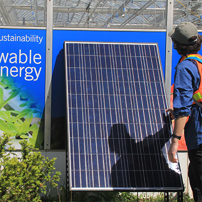 A student inspects a solar panel at the Greenhouse