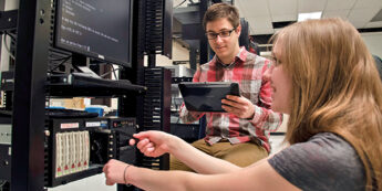 Two students working together using a network diagnostic tool and computer console