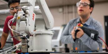 two students using robotic equipment in a lab