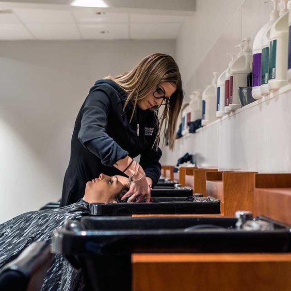 Student rinses hair in hairstyling lab