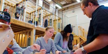 Multiple students with a teaching explaining electrical techniques in a lab on campus.