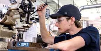 Male student working with a tooling machine in a campus lab.