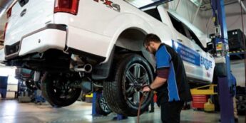Student is engaged in truck maintenance in a garage surrounded by tools and equipment