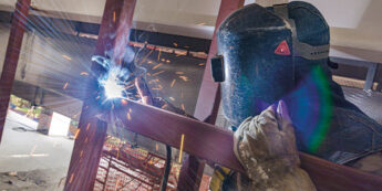 Student wearing protective gear welding a metal beam
