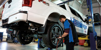 Student is engaged in truck maintenance in a garage surrounded by tools and equipment