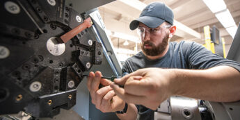 Male student working on inside of a machine.