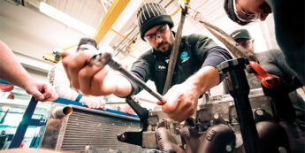 student working with tools on car engine