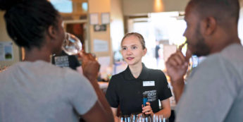 Two visitors taste wine poured by a student sommelier at the NC Wine Visitor and Education Centre