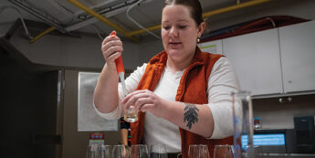 wine and viticulture student putting wine from syringe into wine glass