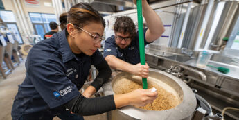 Students mixing in a steel drum in the teaching brewery.