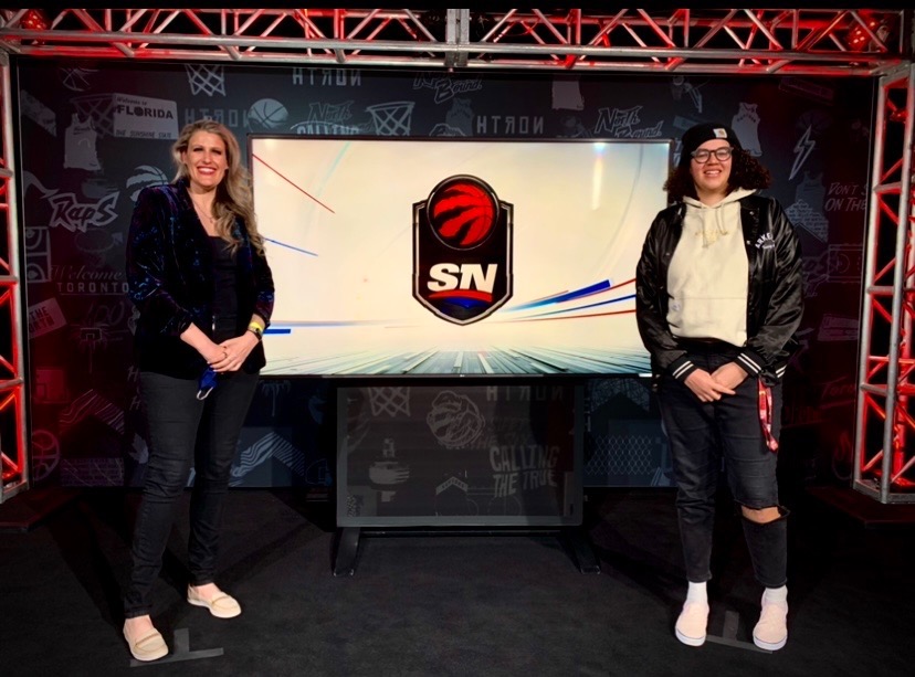Two women standing in front of a TV screen with the Sportsnet logo.