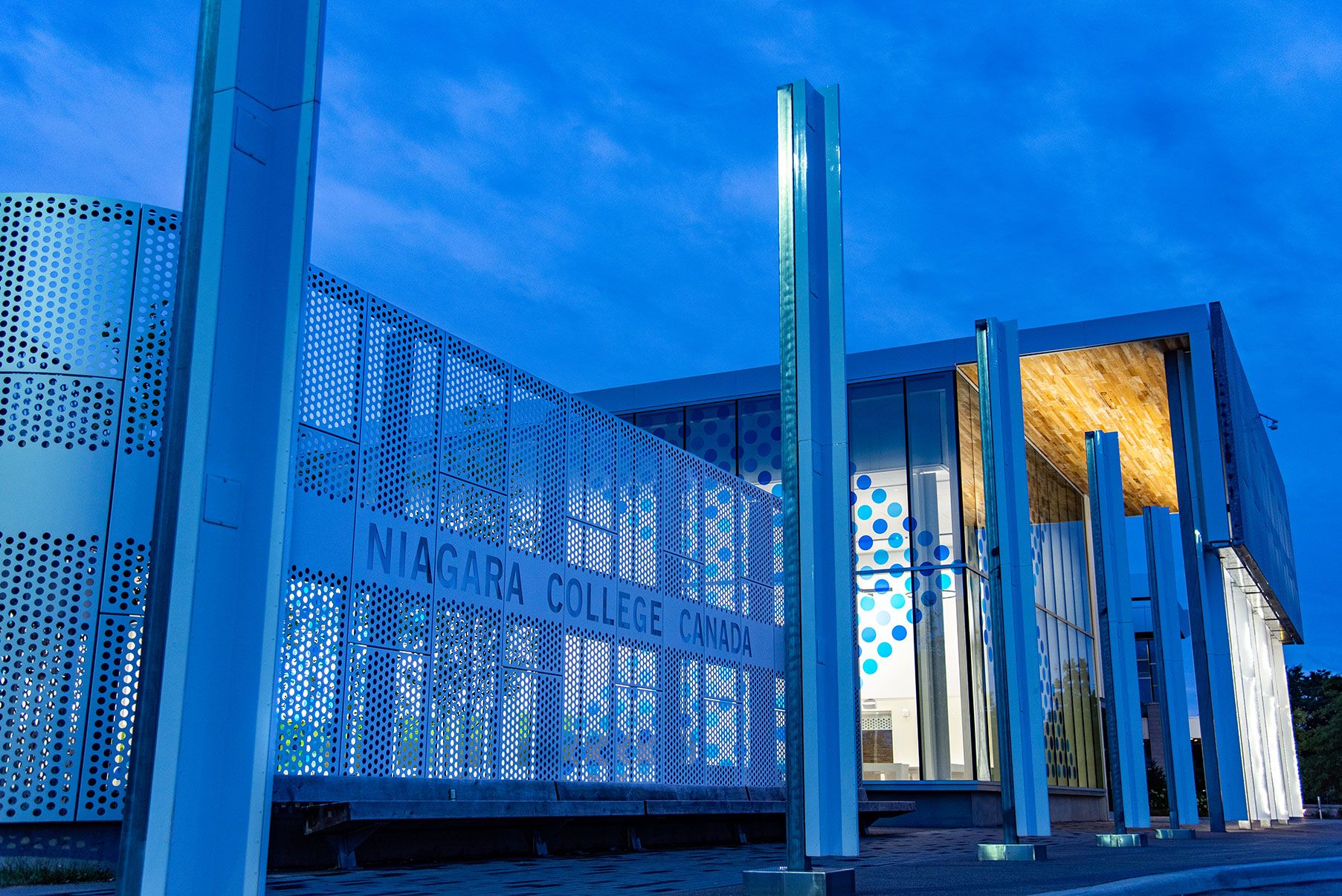 An exterior night time photo of the Niagara College Student Commons building at the Welland Campus