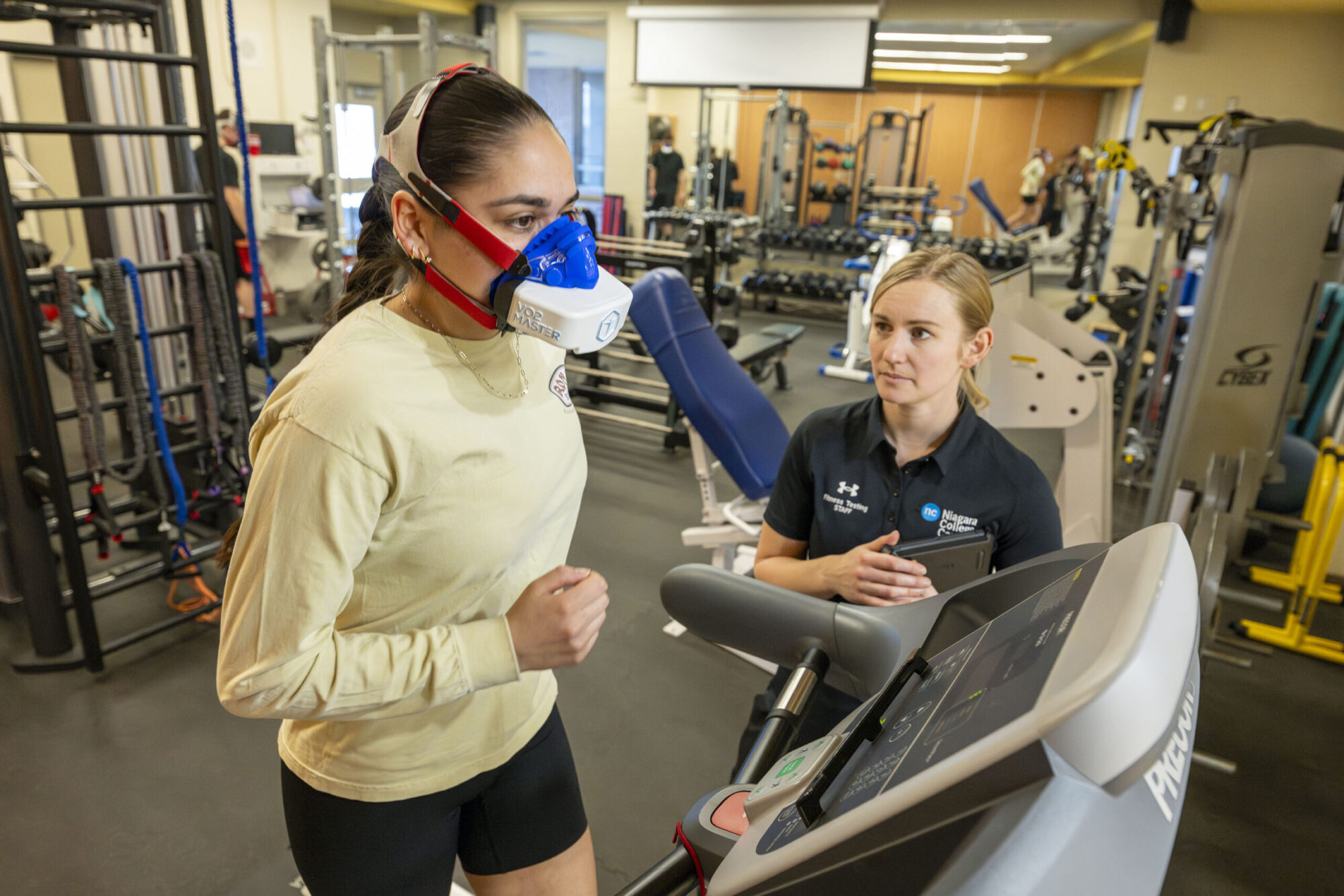 a female student runs on a treadmill wearing a specialized mask