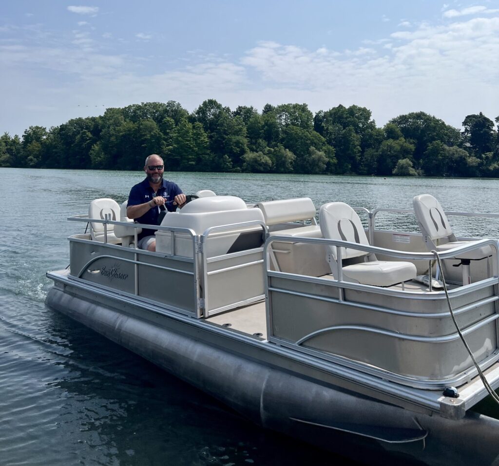 Peter Vandenburg piloting a pontoon boat on a lake