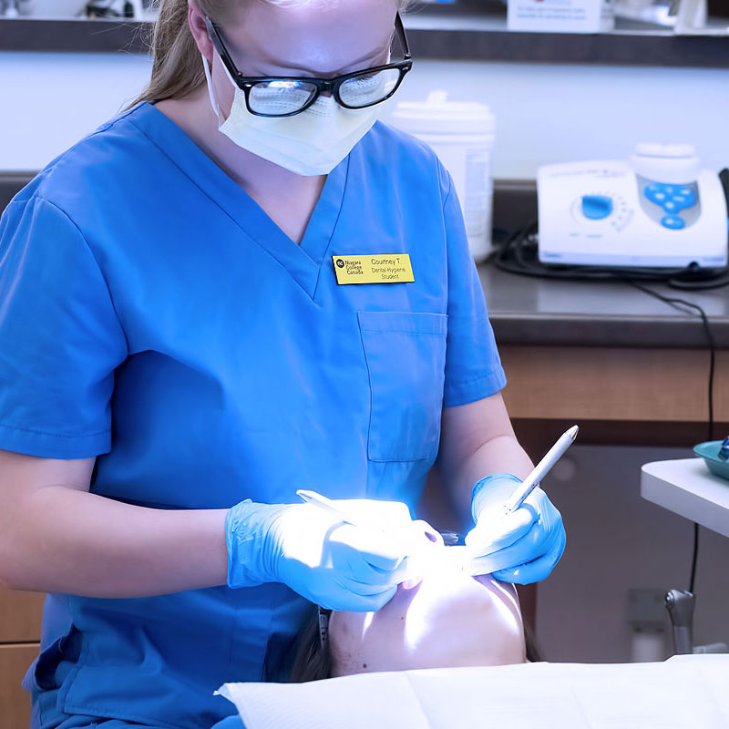 Student dental hygienist cleaning a client's teeth