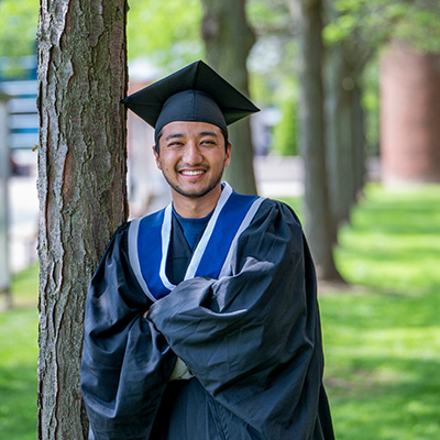 Graduate in gown and cap posing outside the Welland campus