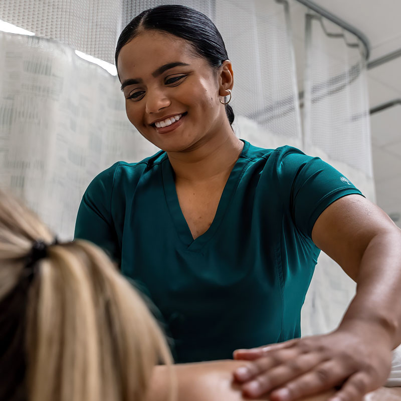 Student in scrubs gives a back massage to a client