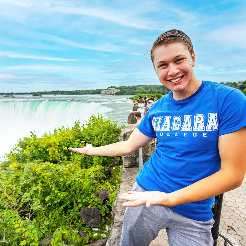 Student wearing NC t-shirt standing in front of Niagara Falls