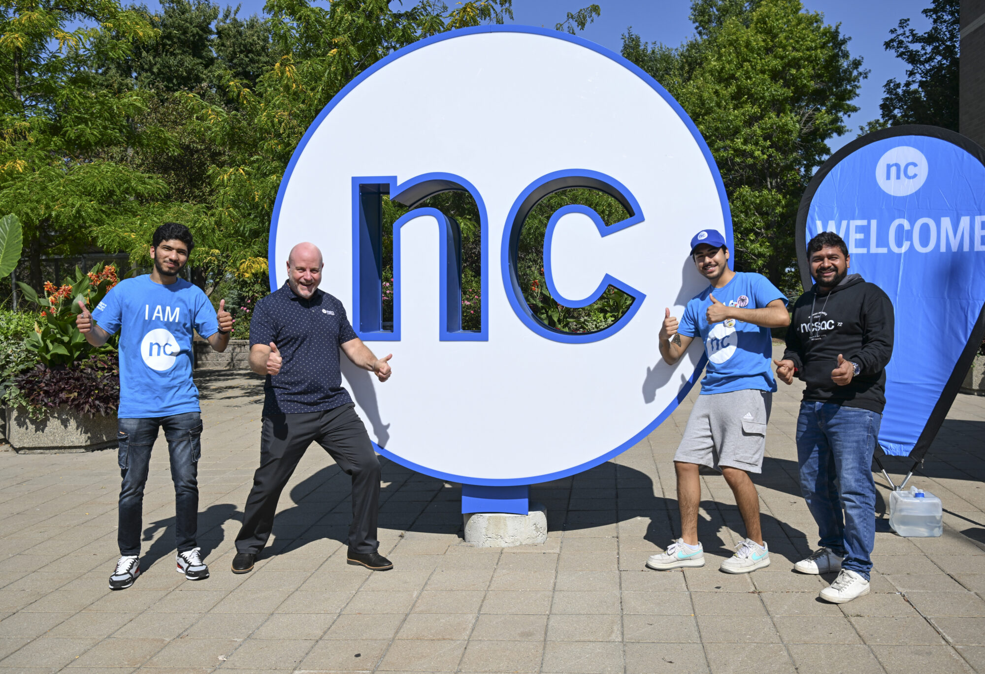 NC President Sean Kennedy stands outside the campus in front of the NC display