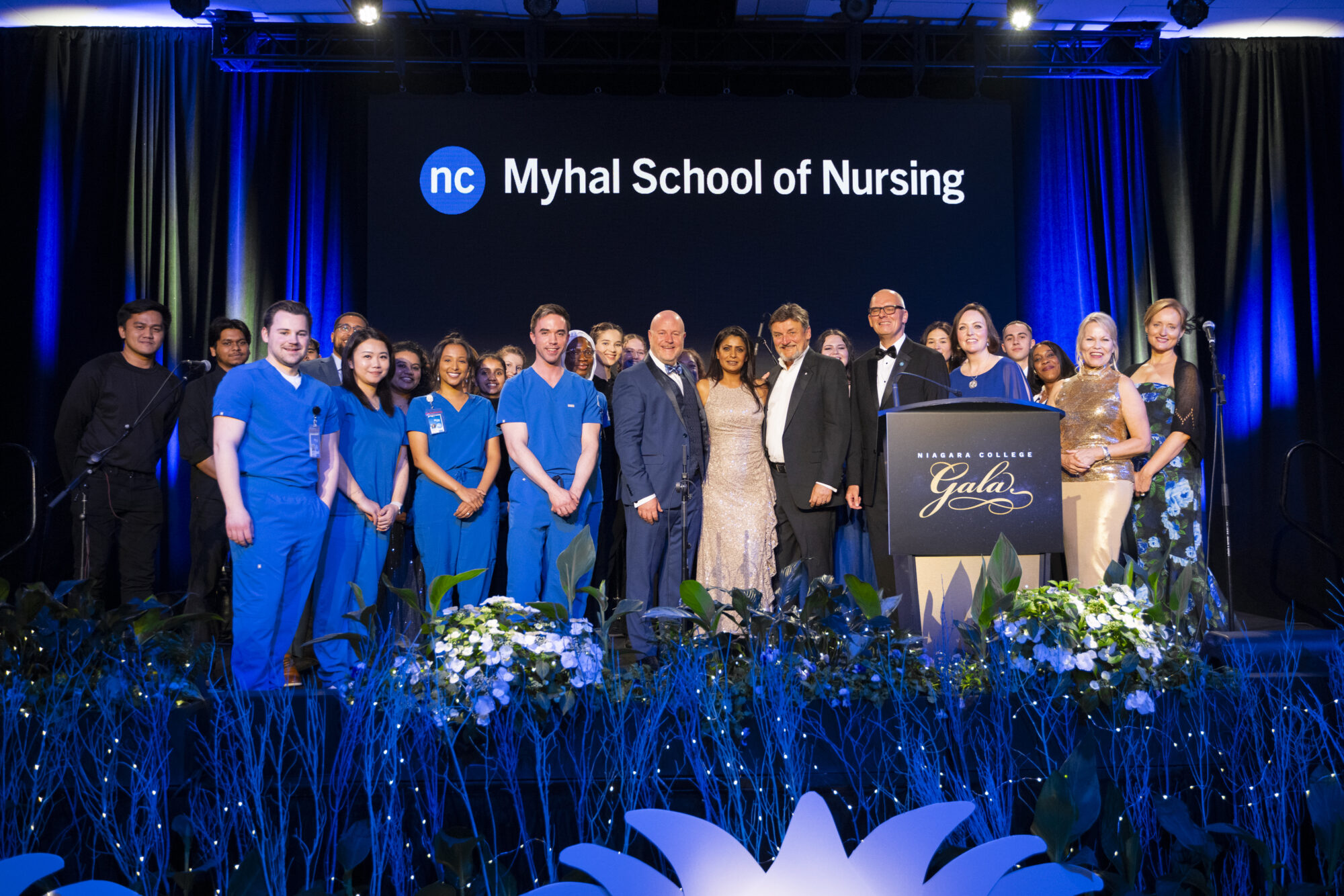 A group of people stand on stage at the Niagara College Gala celebrating a $5M donation from the Myhal Family Foundation.
