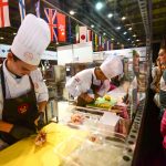 Ben Lillico, David Ross and Robbie Aggarwal are busy in the kitchen as spectators look on.