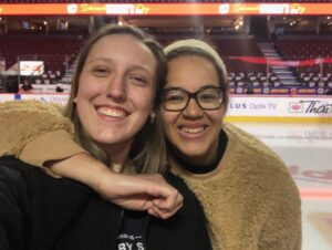 Two women taking a selfie while standing on an NHL ice rink.