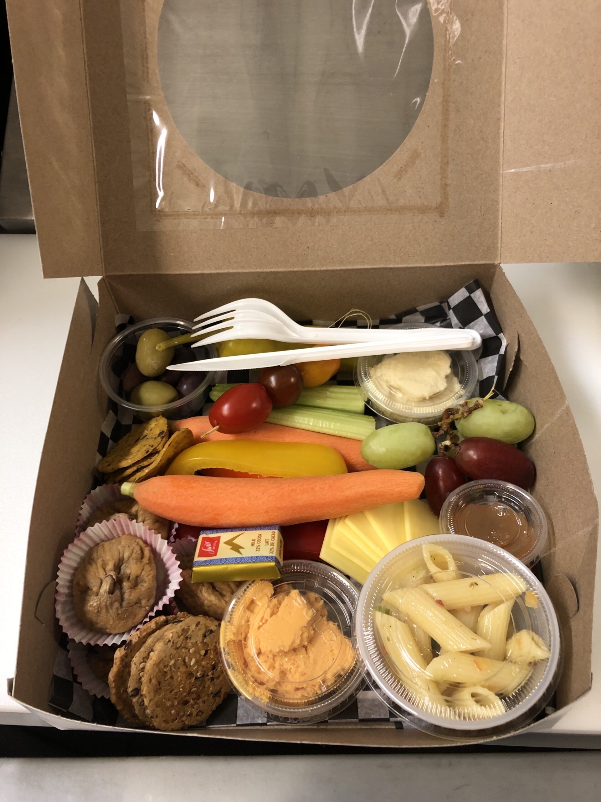 a charcuterie box with a selection of vegetables, fruits, cheeses and crackers