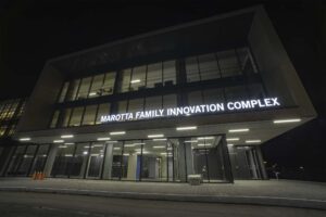 The beautifully modern architecture of the Marotta Family Innovation Complex at night, illuminated from within